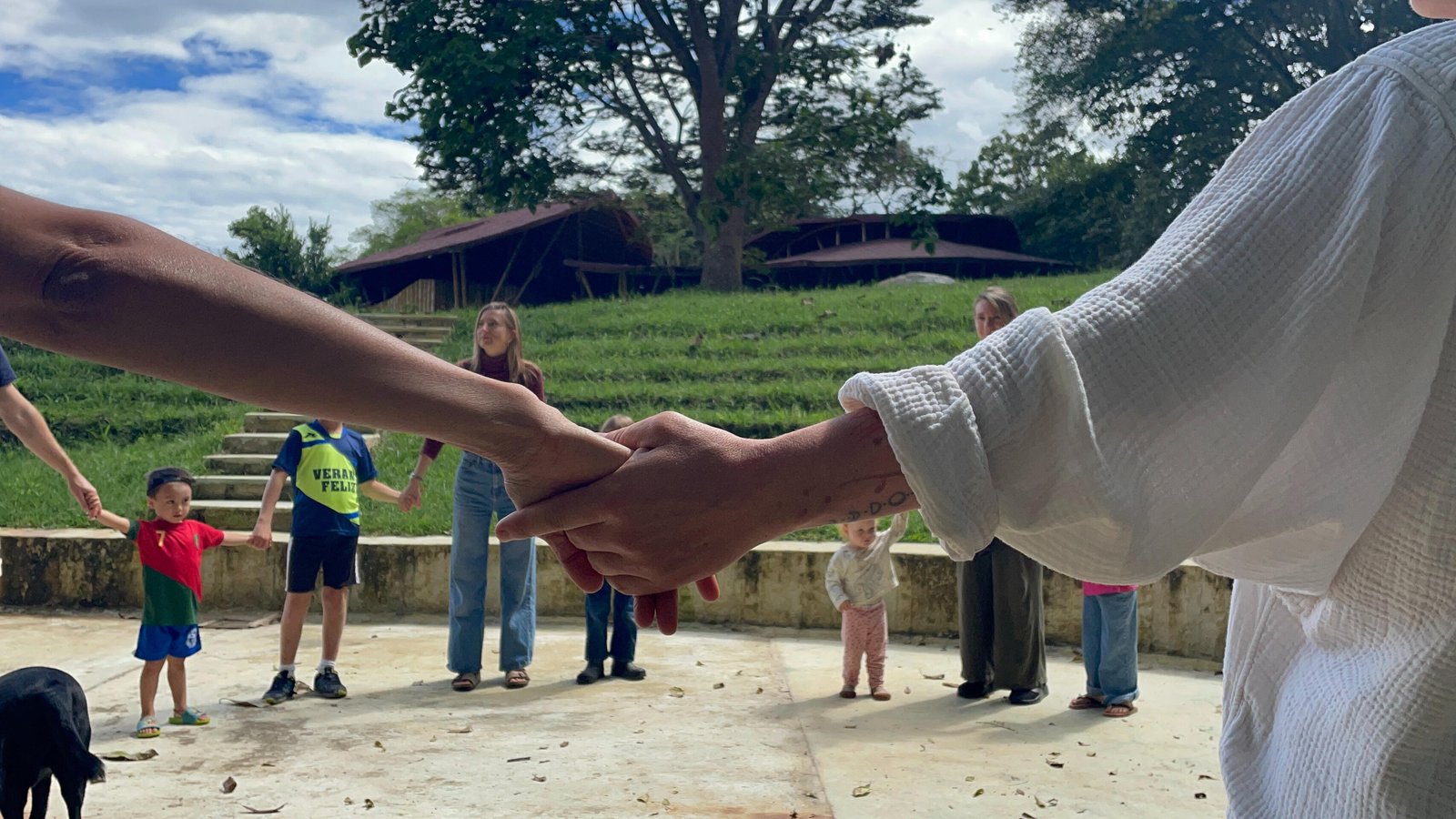 Families holding hands in a circle at Casa Sumapaz