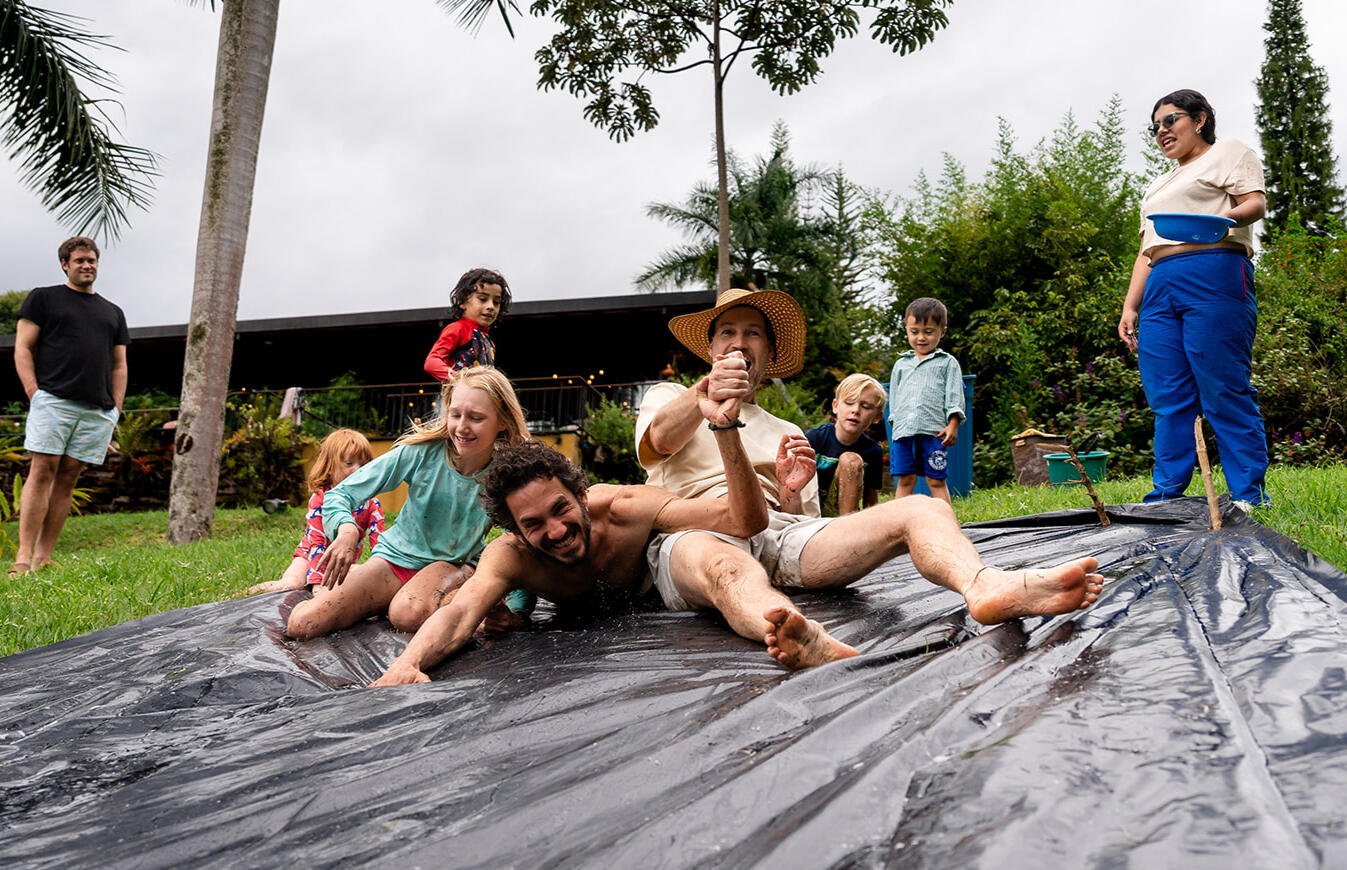 Families playing on a slip-and-slide with the host at Casa Sumapaz