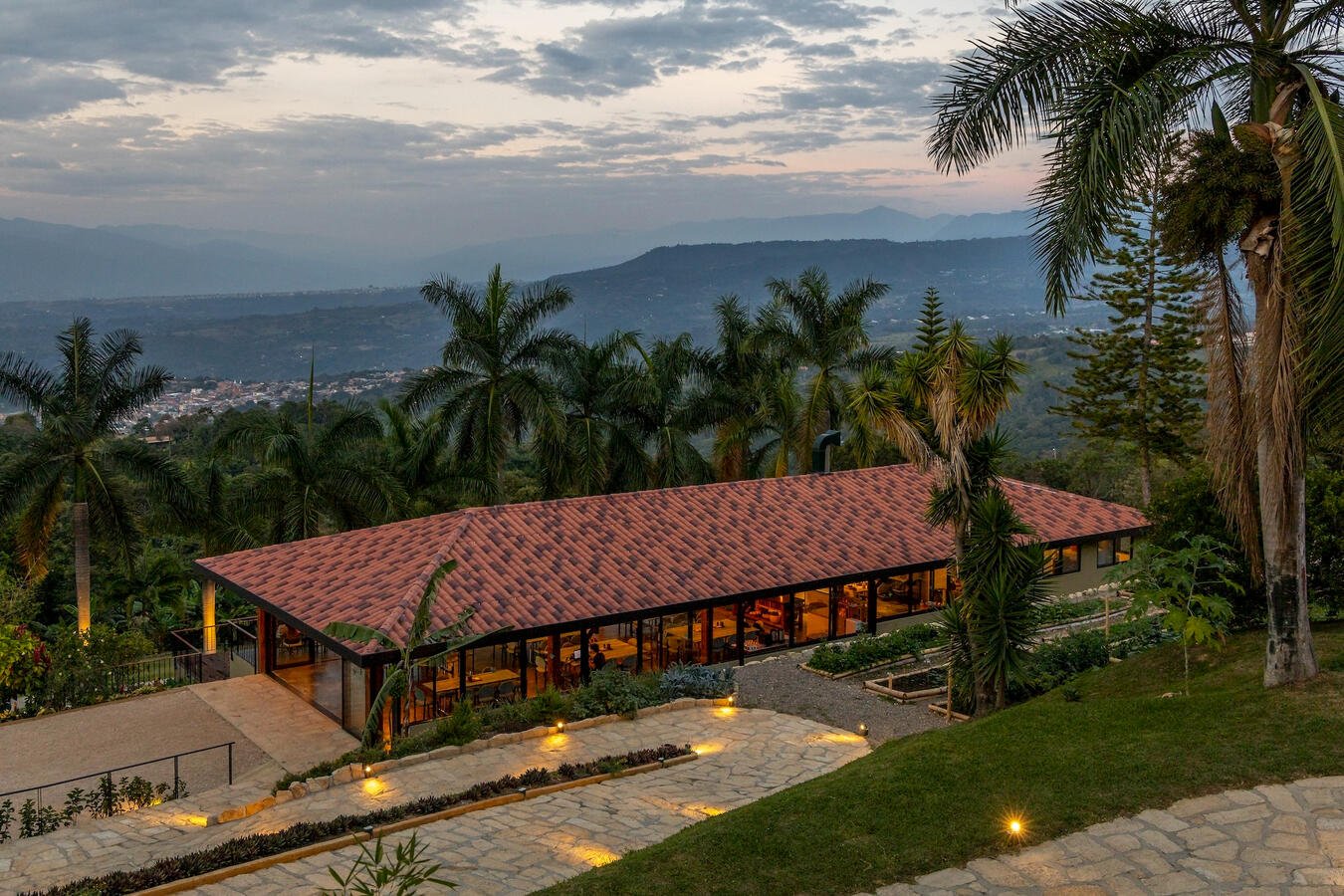 Aerial view of Casa Sumapaz main pavilion at sunset with palms and Andes mountains