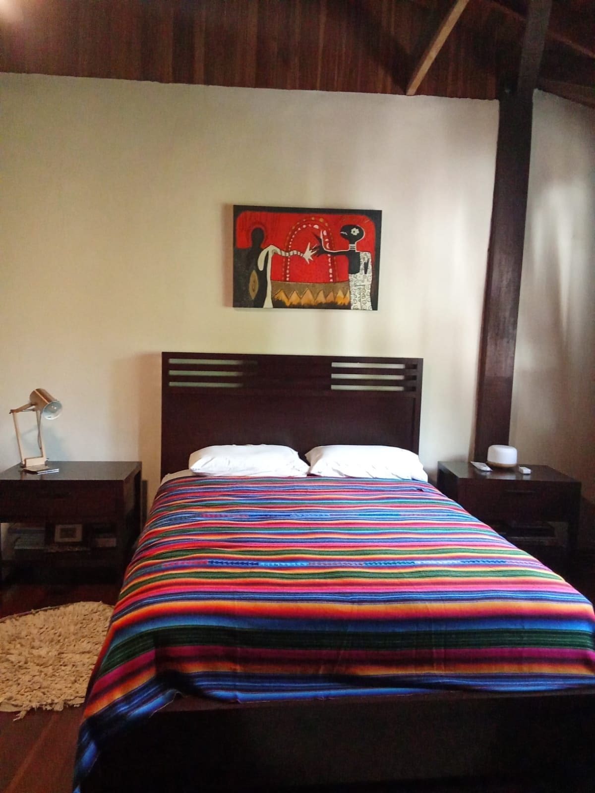 Casa Brisa bedroom with wooden bed and colorful Guatemalan textile